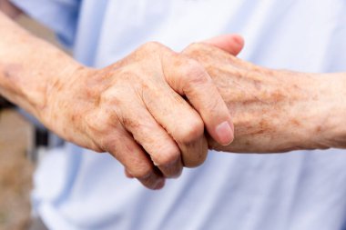 Parlak geçmişi olan yaşlı bir kadının elleri detaylıdır.