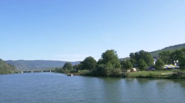 Sakin Moselle nehri, dingin mavi gökyüzünün altında, canlı yeşil bir nehir kıyısından yavaşça akıyor.