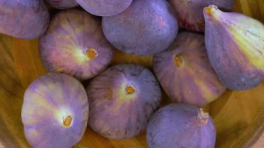 Taze, olgun, tatlı incirlerin tepeden görünüşü yavaşça kırsal bir ahşap kasenin içinde dönüyor.