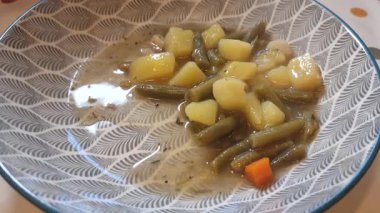 Şef sağlıklı ve lezzetli bir çorbayı yeşil fasulye, patates ve havuçla karıştırır.