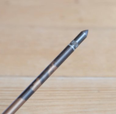 An aluminium arrow with a field tip on a wood backdrop