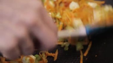 Bir tavadaki sebzeleri spatulayla karıştırma.