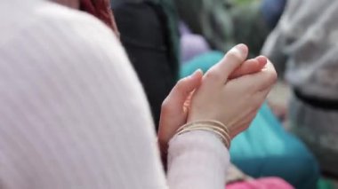 Renkli eşarplı, bilezikli bir kadının ellerini çırpıyor.