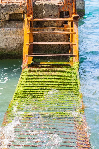 Een roestig ladder in het water — Stockfoto