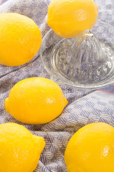 Lemons and lemon squeezer on a kitchen towel — Stock Photo, Image