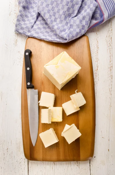 Cubos de mantequilla y cuchillo de cocina en una tabla de madera —  Fotos de Stock