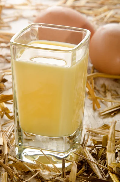 Licor de huevo, vaso de chupito y huevos frescos en la paja —  Fotos de Stock