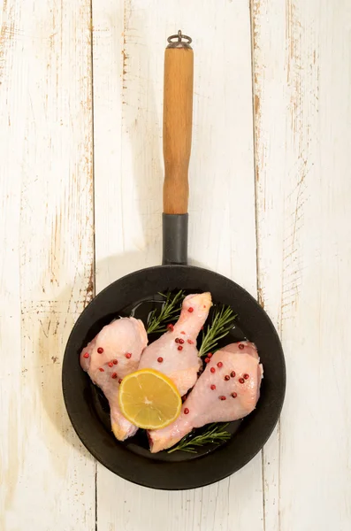 Pilon de poulet cru au poivre rouge, tranche de citron et de rose — Photo