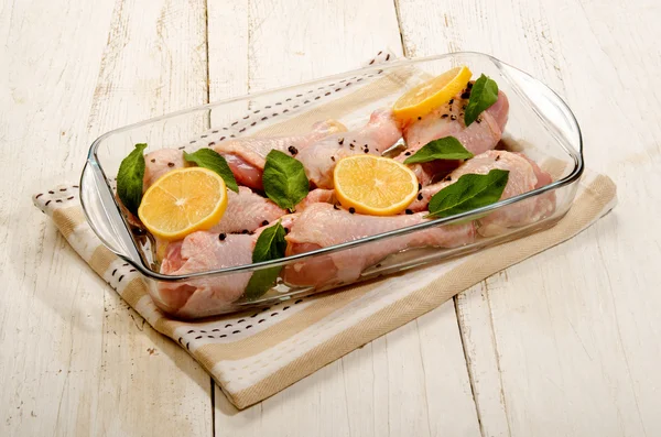 Raw chicken drumstick with sage and lemon in a glass bowl — Stock Photo, Image