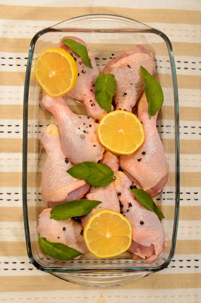 Raw chicken drumstick with sage and lemon in a glass bowl — Stock Photo, Image