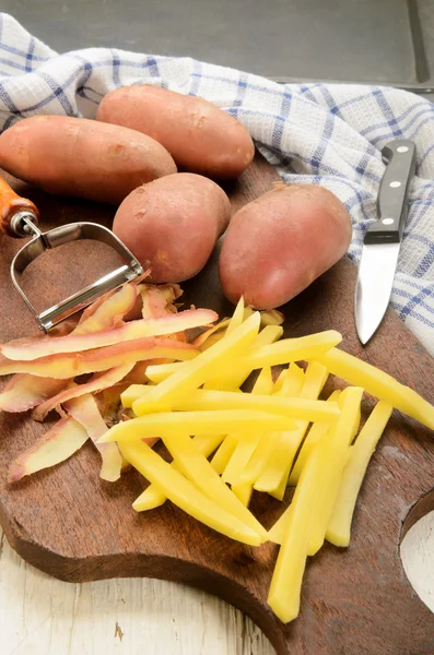 Freshly cut french fries on a wooden board — Stock Photo, Image