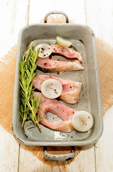 Fresh carp steaks with onion rings and rosemary in a roasting ti — Stock Photo, Image