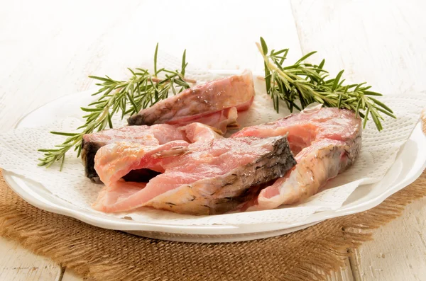 Raw carp steak with paper kitchen towel and rosemary — Stock Photo, Image