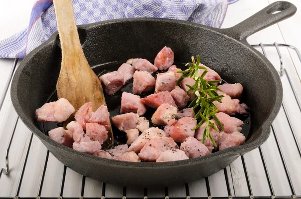 Roasted bacon cubes with rosemary in a cast iron pan — Stock Photo, Image