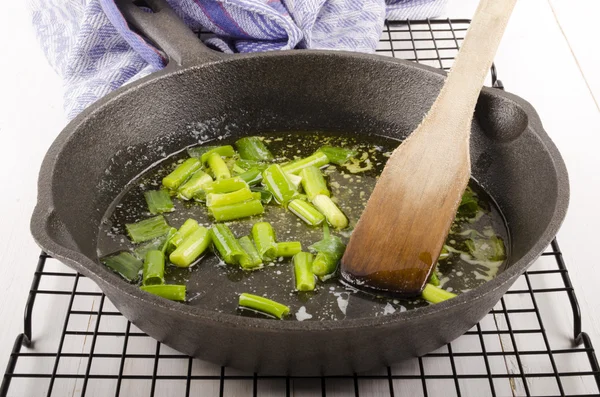Lente-uitjes worden bereid in een gietijzeren pan met warme boter — Stockfoto