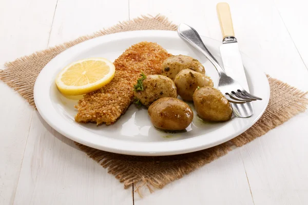 Havermout gepaneerd kipper en baby aardappelen met kruiden — Stockfoto