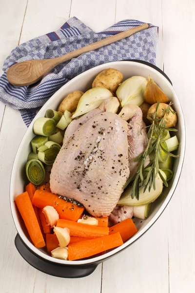 Frango cru inteiro com verduras em um prato assado — Fotografia de Stock