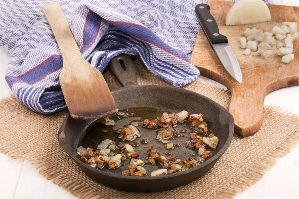 Жареный лук с маслом в чугунной сковороде — стоковое фото