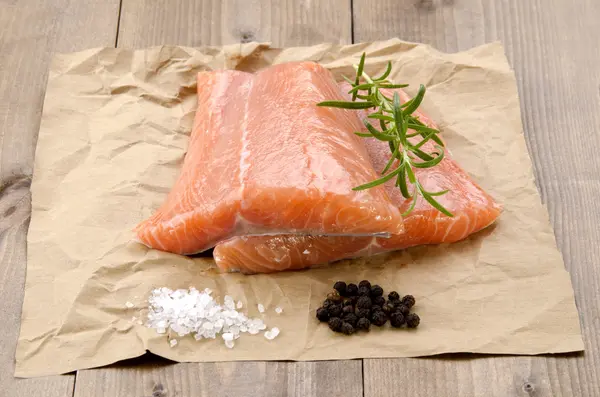 Filetto di salmone fresco con rosmarino su carta marrone — Foto Stock