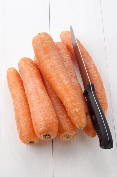 Cenouras e uma faca de cozinha usada — Fotografia de Stock