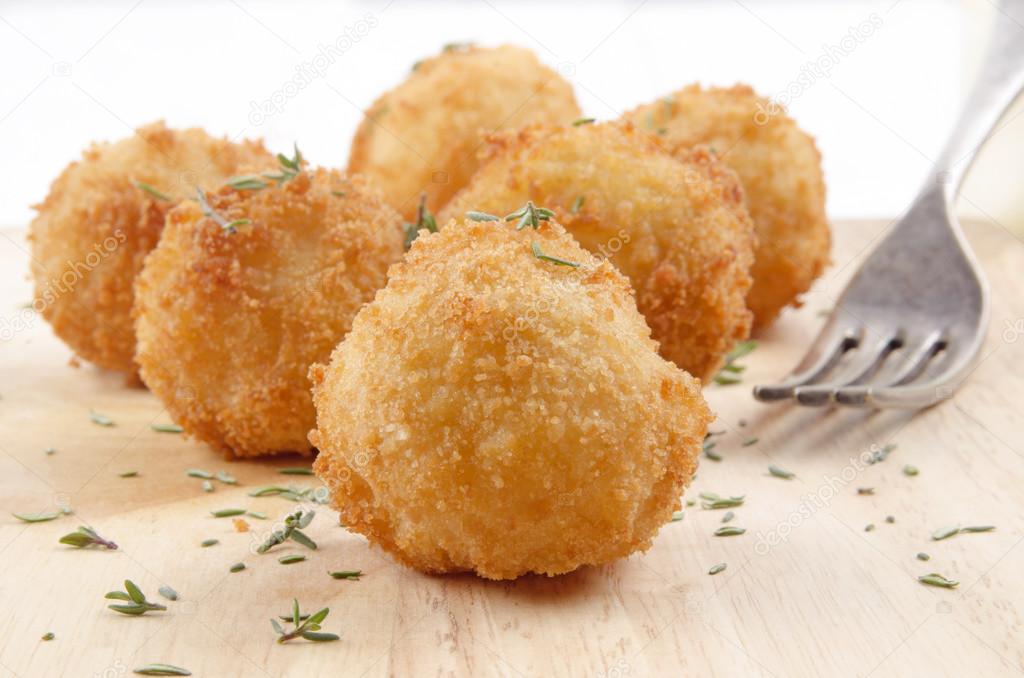 fried potato balls with thyme and fork