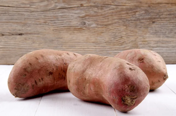 Raw organic sweet potato on white wood — Stock Photo, Image