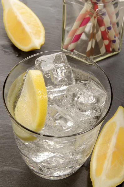 Mineral water with ice cubes and slice of lemon in a glass — Stock Photo, Image