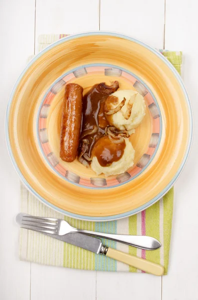 Mashed potato with gravy and sausage on a plate — Stock Photo, Image