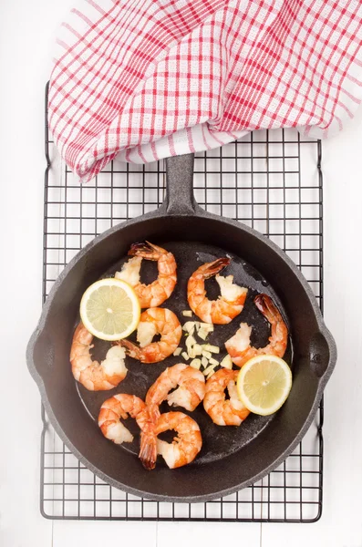 Langostinos con rodaja de limón y ajo en una sartén — Foto de Stock