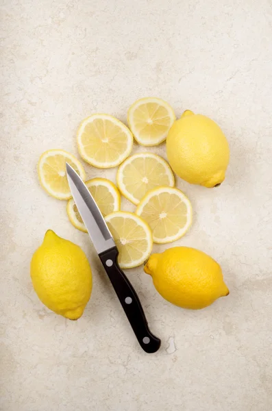 Cytryny, plasterki cytryny i kitchen knife — Zdjęcie stockowe