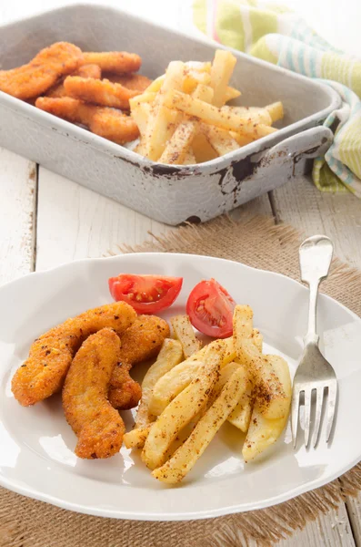 Pepitas de frango empanadas, batatas fritas e tomate em um prato — Fotografia de Stock