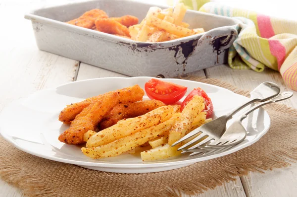 Хлібні курячі нагетси, картопля фрі та помідор на тарілці — стокове фото
