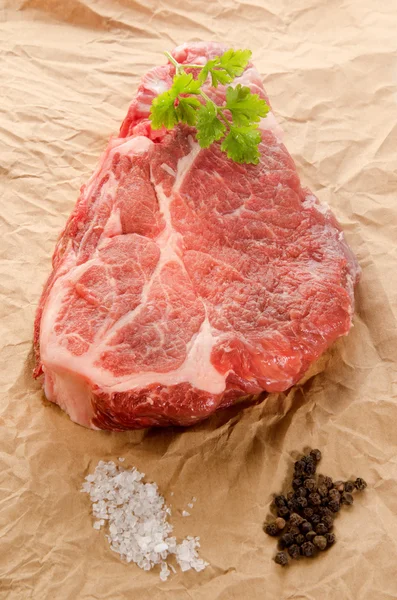 Raw marbled pork steak with coarse salt, pepper and parsley — Stock Photo, Image
