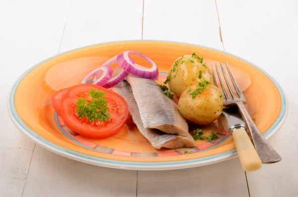 Sleď matjes a vařenými brambory s rajčaty na talíři — Stock fotografie