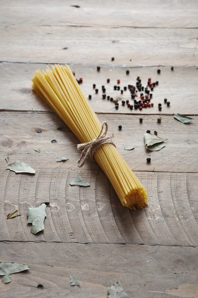 Cooking concept. Uncooked italian pasta: vermicelli, spaghetti with twine and tomato on wooden background — Stock Photo, Image