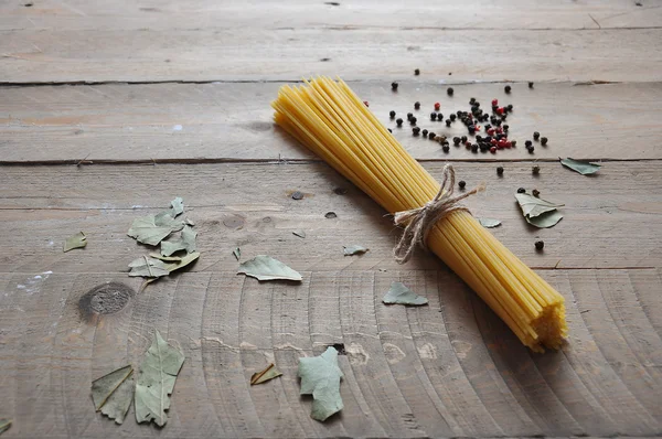 Cooking concept. Uncooked italian pasta: vermicelli, spaghetti with twine and tomato on wooden background — Stock Photo, Image