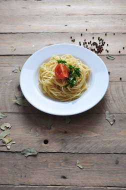 Spagetti domates, biber, baharat ve otlar ahşap arka plan üzerinde bir plaka üzerinde