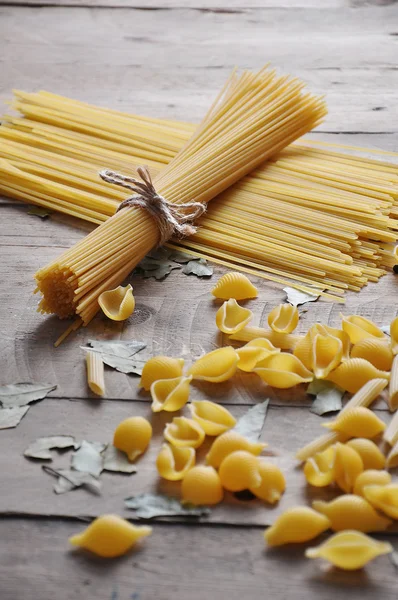 Pişirme kavramı. Pişmemiş makarna çeşitleri: erişte, sicim ahşap zemin üzerine spagetti — Stok fotoğraf