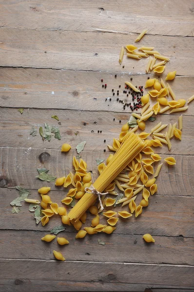 Pişirme kavramı. Pişmemiş makarna çeşitleri: erişte, sicim ahşap zemin üzerine spagetti — Stok fotoğraf