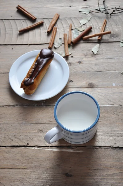 Exquisite sobremesa creme eclair polvilhado com chocolate e leite na madeira — Fotografia de Stock