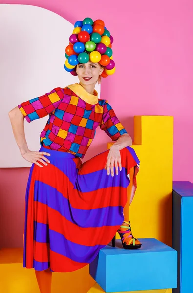 Attractive young woman dressed in colored clothes in a hat made of colorful ball
