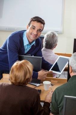 C son sınıf öğrencileri için dijital Tablet gösteren kendine güvenen öğretmen