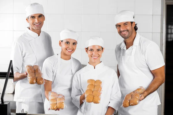 Pekaři ukazující balené pečivo v pekárně — Stock fotografie