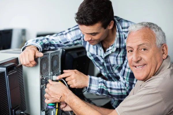 Happy Senior Man with Teacher Installing Computer In Classroom — стоковое фото