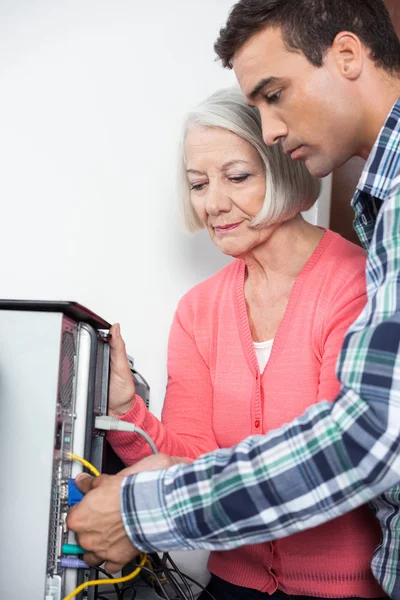 Informator bistå äldre kvinna konfigurera dator — Stockfoto