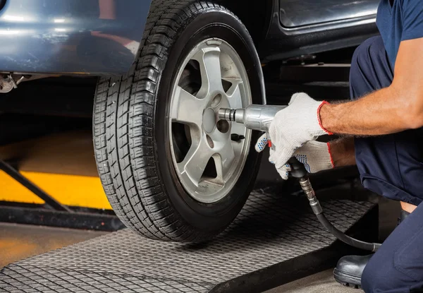 Pneu do carro do parafuso do técnico com chave pneumática — Fotografia de Stock