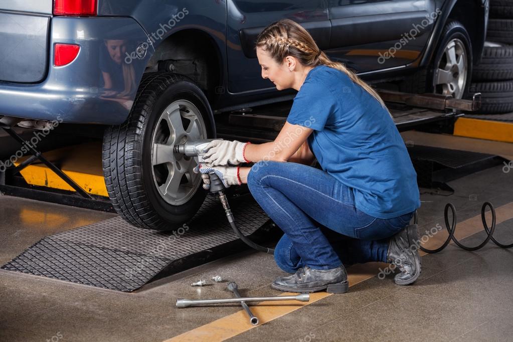 Female Mechanic Fixing Car Tire With Pneumatic Wrench — Stock