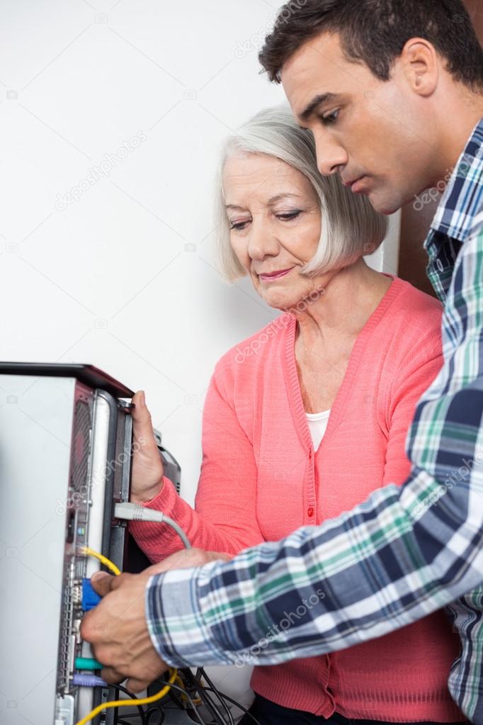 Tutor Assisting Senior Woman Setting Up Computer