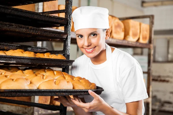 Bäckerin hält Backblech in Backstube — Stockfoto