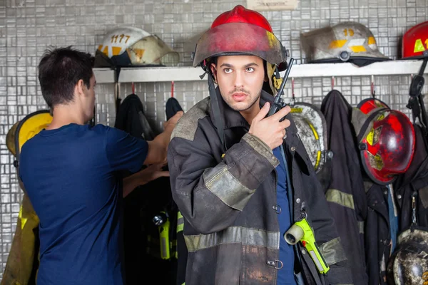 Firefighter Using Walkie Talkie With Colleague In Background — Stock Photo, Image